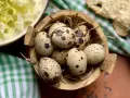 Un cesto di paglia contiene uova di quaglia sode, pronte per essere gustate. Accanto, un'insalata fresca e pane.