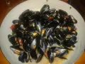 Un'abbondante impepata di cozze in un piatto largo, con pomodorini e un sughetto invitante.