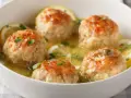Polpette al limone dorate e succulente, servite in una ciotola bianca con fette di limone e prezzemolo tritato.