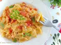 Farfalle cremose con pomodorini e salmone, guarnite con prezzemolo fresco. Un piatto invitante pronto per essere gustato.
