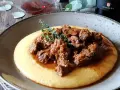 Un piatto di gulash con polenta fumante, guarnito con rametti di timo fresco. Un classico confortante, perfetto per una cena speciale.