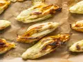Fiori di zucca in pastella dorati e croccanti, appena sfornati su carta da forno.