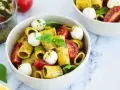 Un piatto di pasta pesto e pomodorini, con mozzarelline e basilico fresco. Un'esplosione di sapori mediterranei.