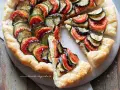 Una deliziosa torta salata estiva con zucchine, melanzane e pomodori disposti a raggiera su una base croccante.