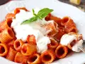 Rigatoni al sugo con abbondante stracciatella cremosa e una fogliolina di basilico fresco.