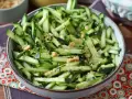 Una ciotola piena di fresca insalata di cetrioli tagliati a julienne, condita con semi di sesamo e arachidi croccanti.