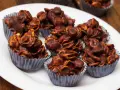Deliziosi biscotti corn flakes e cioccolato, croccanti e golosi, serviti in pirottini argentati su un piatto bianco.