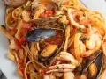 Un piatto invitante di scialatielli ai frutti di mare, con gamberi, cozze, vongole e calamari in un sugo rosso.