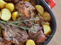 Agnello al forno con patate dorate e rosmarino, un piatto succulento pronto per essere gustato.