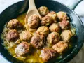 Polpette in bianco dorate e succulente, cotte in padella con cipolle dolci e un sughetto invitante. Un classico confortante.