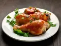 Tre succulenti cosce di pollo alla birra in padella, glassate e guarnite con erbe aromatiche e cipollotto.