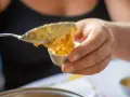 Una mano versa un cucchiaio di budino di riso in una coppetta.