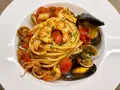 Un piatto invitante di spaghetti allo scoglio, con gamberi, cozze, vongole e calamari, condito con pomodorini freschi e prezzemolo.