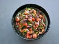 Una ciotola di insalata di lenticchie colorata con pomodori, cipolla rossa e erbe fresche.