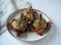 Tre carciofi alla giudia dorati e croccanti su un piatto, pronti per essere gustati.