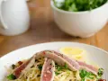 Spaghetti con tonno fresco alla siciliana, guarniti con rucola, capperi, pomodori secchi e una fetta di limone.