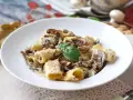 Un piatto invitante di pasta funghi e panna, con rigatoni conditi generosamente e guarniti con basilico fresco.