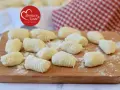 Gnocchi di ricotta freschi, pronti per essere cucinati, spolverati di farina su un tagliere di legno.