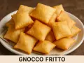 Un piatto colmo di gnocco fritto dorato e soffice, pronto per essere gustato.