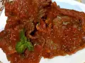 Fette di carne alla pizzaiola, ricoperte da un sugo rosso saporito e guarnite con basilico fresco.