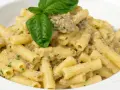 Un piatto invitante di pasta con melanzane in bianco cremosa, guarnito con basilico fresco.