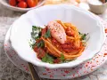 Spaghetti con gamberetti e pomodorini alla siciliana, un piatto colorato e saporito, guarnito con prezzemolo fresco.