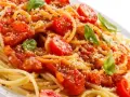Un piatto di spaghetti alla carrettiera, conditi con pomodoro fresco, basilico e parmigiano grattugiato.
