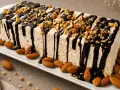 Delizioso parfait di mandorle, ricoperto di cioccolato fuso e granella croccante. Mandorle intere decorano il piatto.