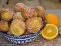 Arancini dolci, soffici arrubiolus di ricotta cosparsi di zucchero, accanto a fette d'arancia.