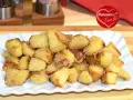 Patate sabbiose in padella, dorate e croccanti, servite su un piatto bianco. Un contorno irresistibile.
