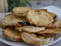 Piatto di melanzane fritte pastellate, dorate e croccanti, pronte per essere gustate.