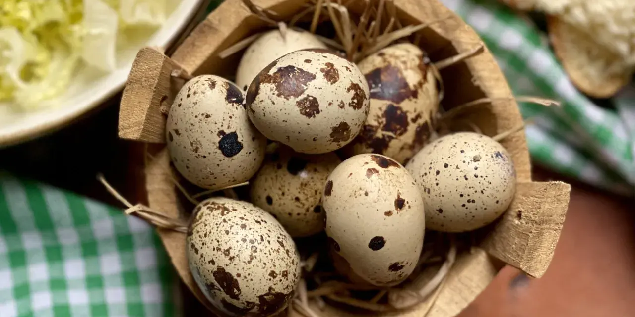 Un cesto di paglia contiene uova di quaglia sode, pronte per essere gustate. Accanto, un'insalata fresca e pane.