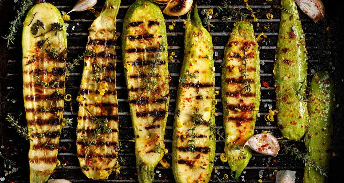 Zucchine grigliate perfette, condite con erbe aromatiche, aglio e scorza di limone, pronte per essere gustate.