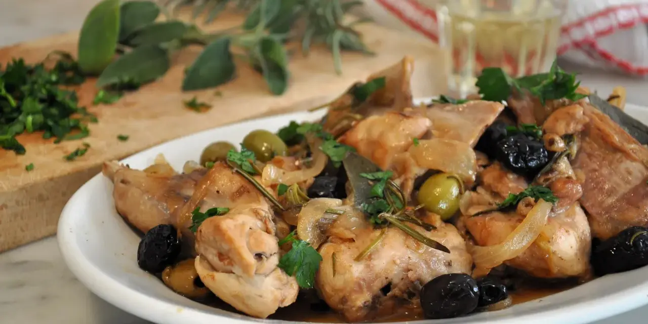 Piatto di coniglio alla cacciatora in bianco, con olive verdi e nere, cipolle e rosmarino.