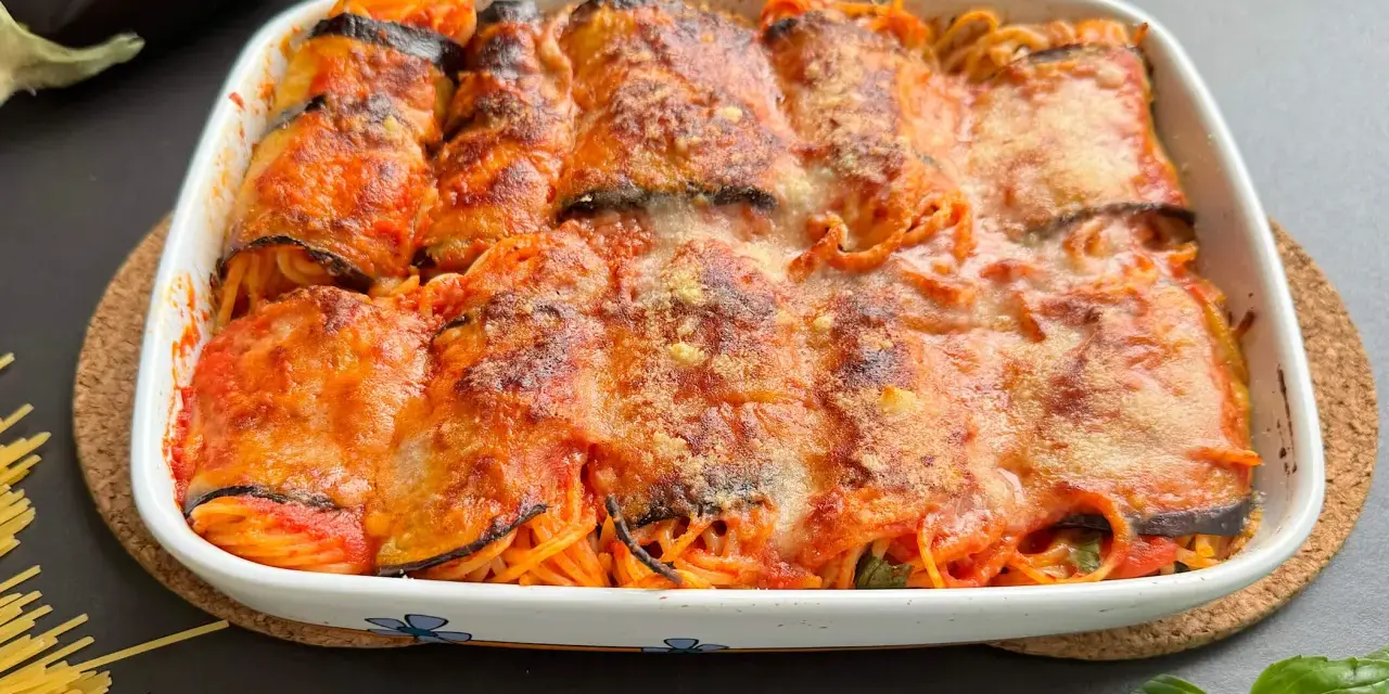 Involtini di melanzane con spaghetti al forno, ricoperti di sugo e formaggio filante, pronti per essere gustati.