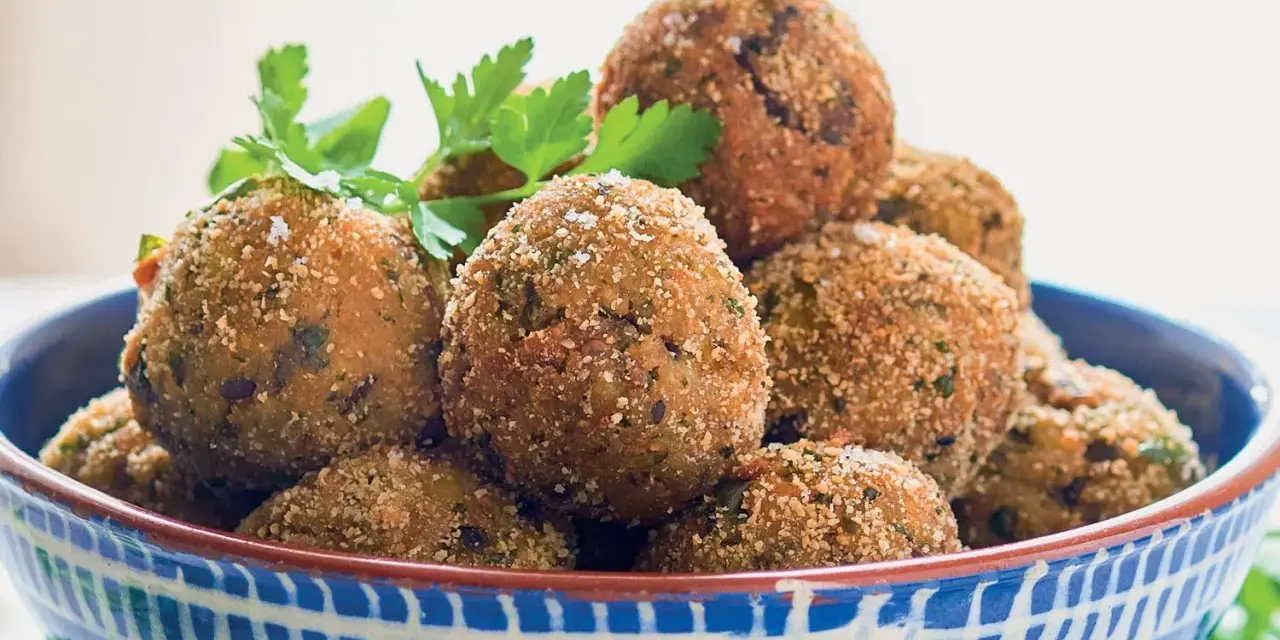 Polpette di melanzane dorate e croccanti, guarnite con prezzemolo fresco, in una ciotola blu decorata.