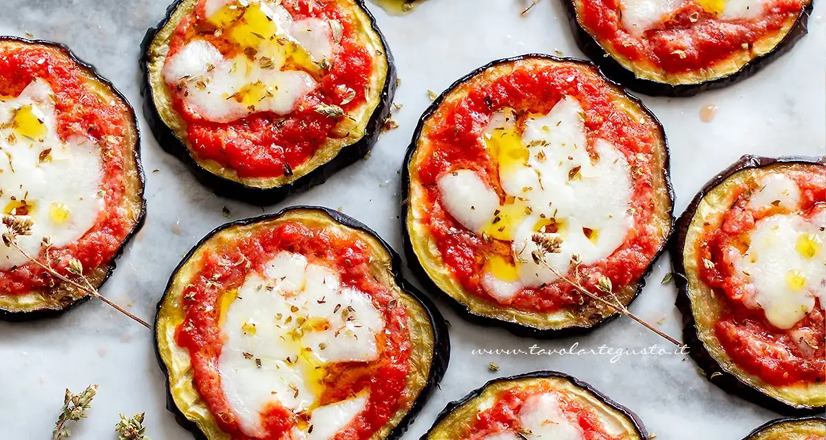 Pizzette di melanzane al forno, con pomodoro, mozzarella filante e un filo d'olio. Un antipasto sfizioso e leggero.