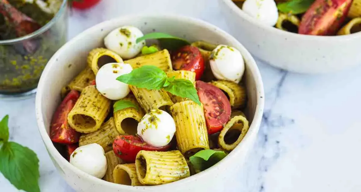 Un piatto di pasta pesto e pomodorini, con mozzarelline e basilico fresco. Un'esplosione di sapori mediterranei.