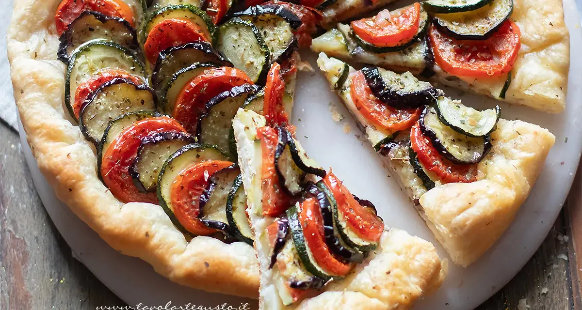 Una deliziosa torta salata estiva con zucchine, melanzane e pomodori disposti a raggiera su una base croccante.