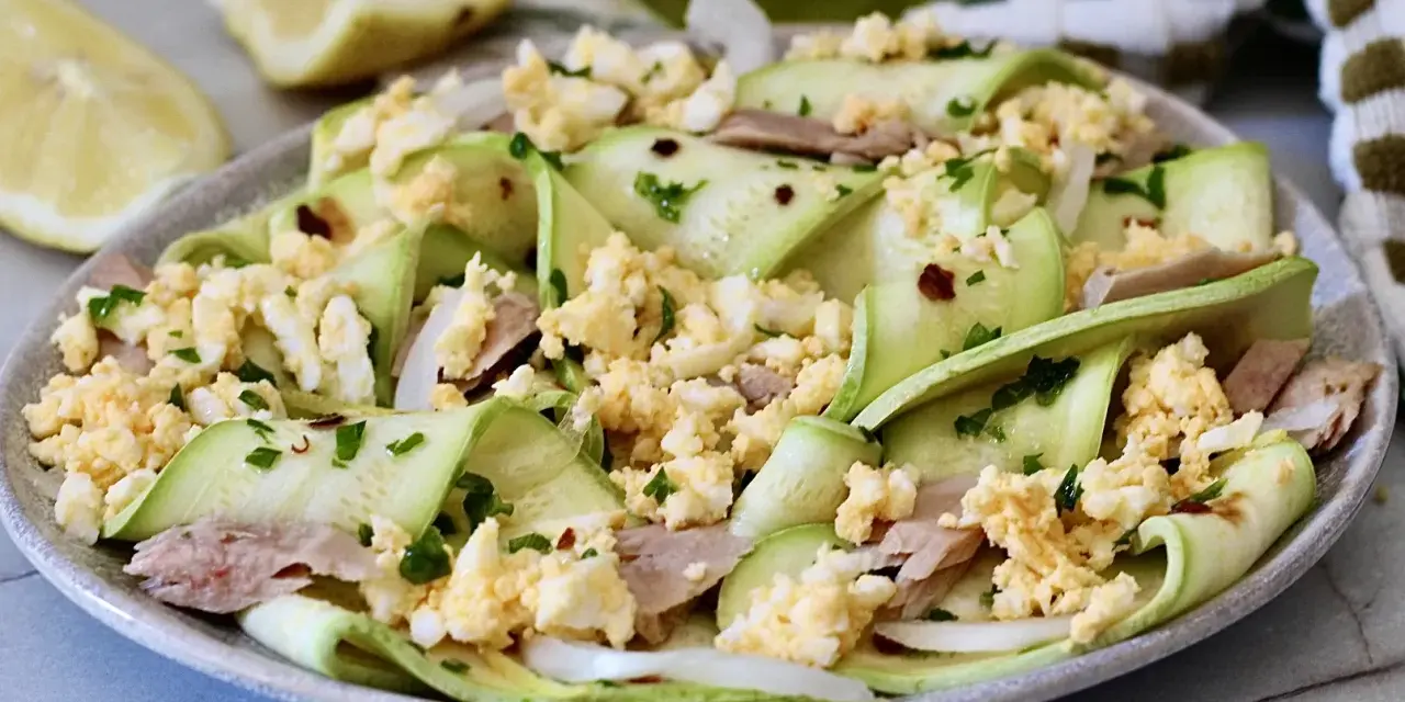 Deliziosa insalata di zucchine crude a nastro, condita con tonno, uova sode sbriciolate e prezzemolo fresco.