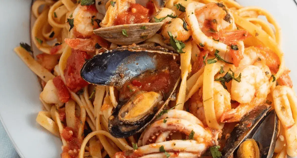 Un piatto invitante di scialatielli ai frutti di mare, con gamberi, cozze, vongole e calamari in un sugo rosso.