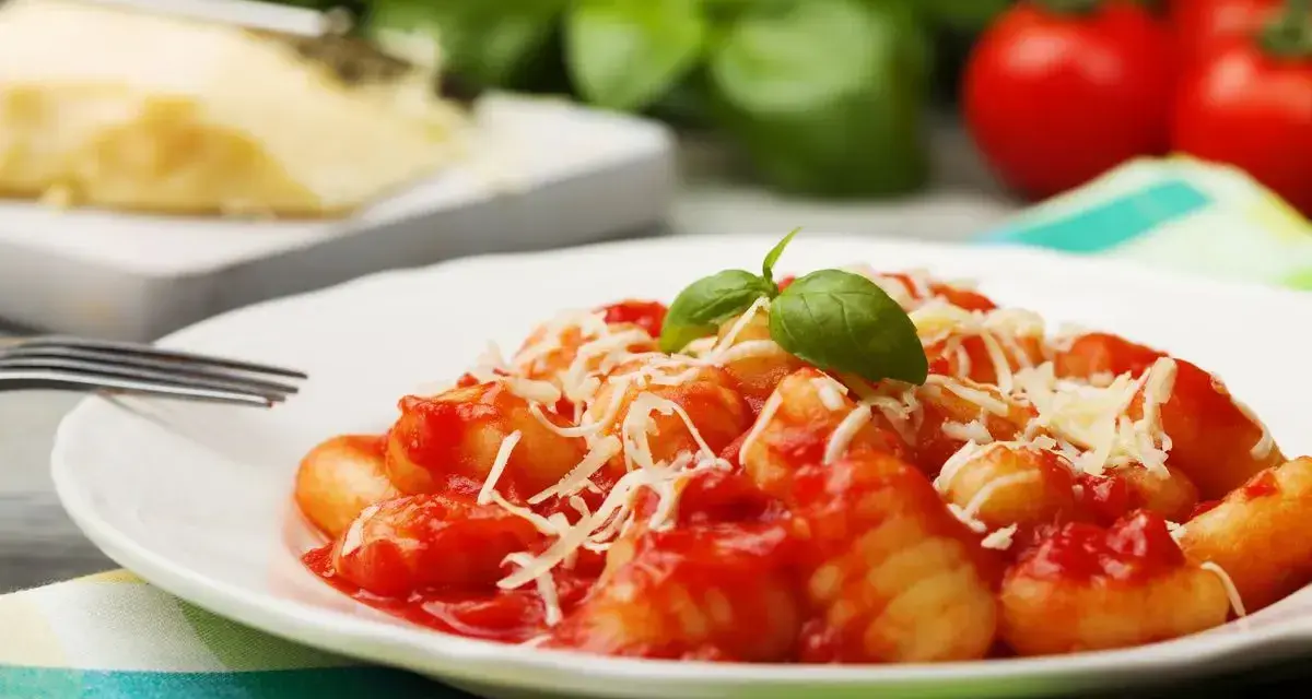 Gnocchi al pomodoro, un piatto semplice e gustoso, con basilico fresco e parmigiano grattugiato.