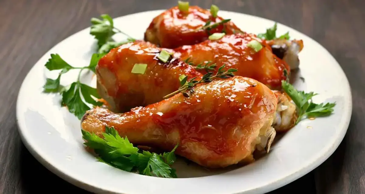 Tre succulenti cosce di pollo alla birra in padella, glassate e guarnite con erbe aromatiche e cipollotto.