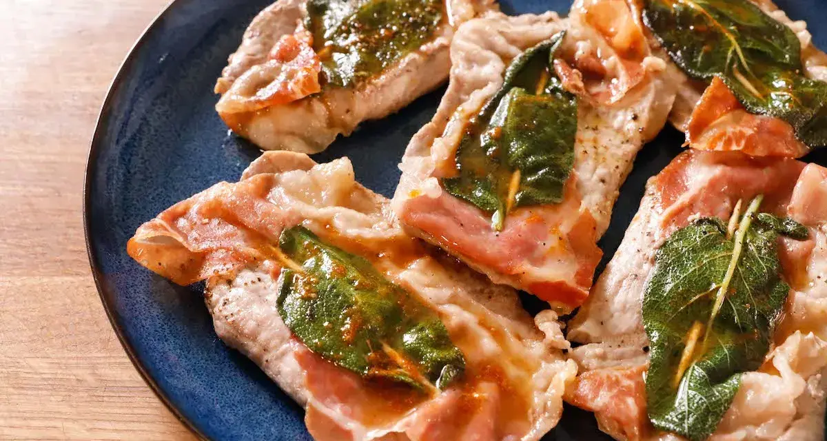 Saltimbocca alla romana: fettine di vitello con prosciutto crudo e salvia, cotte in padella con un sughetto dorato.