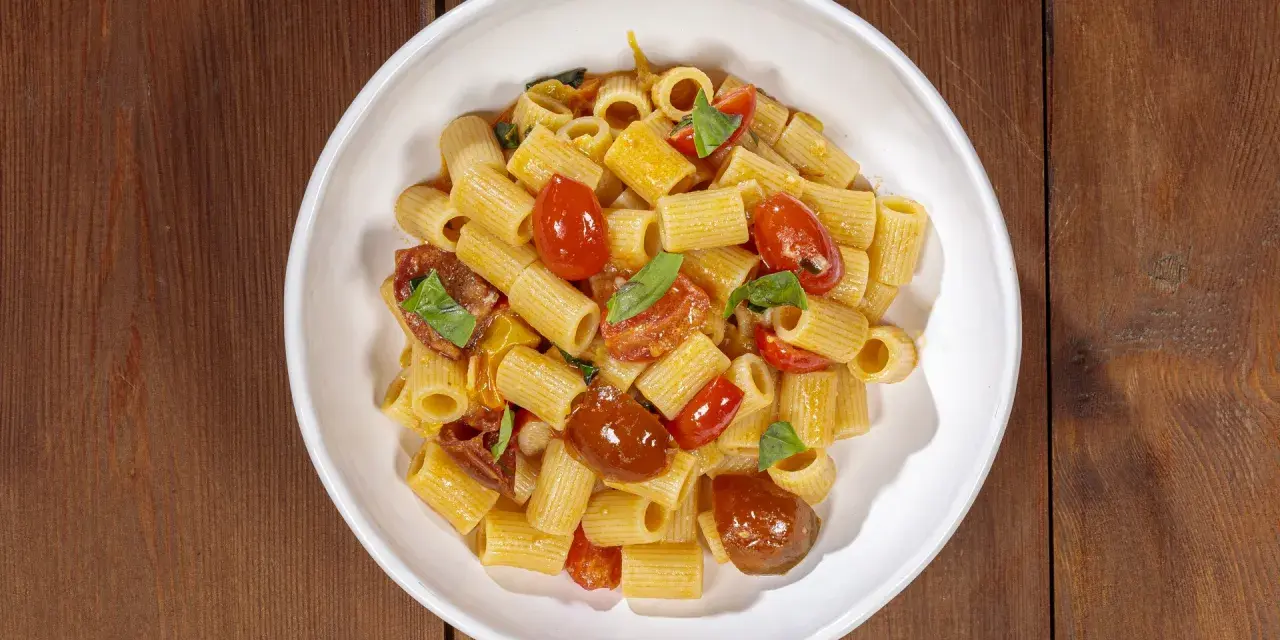 Un piatto invitante di pasta con pomodorini freschi, basilico e un filo d'olio.