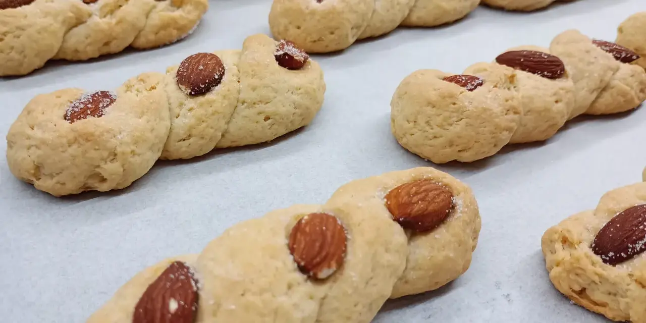Intorchiate pugliesi ricetta originale: biscotti intrecciati dorati con mandorle e zucchero, pronti per essere gustati.