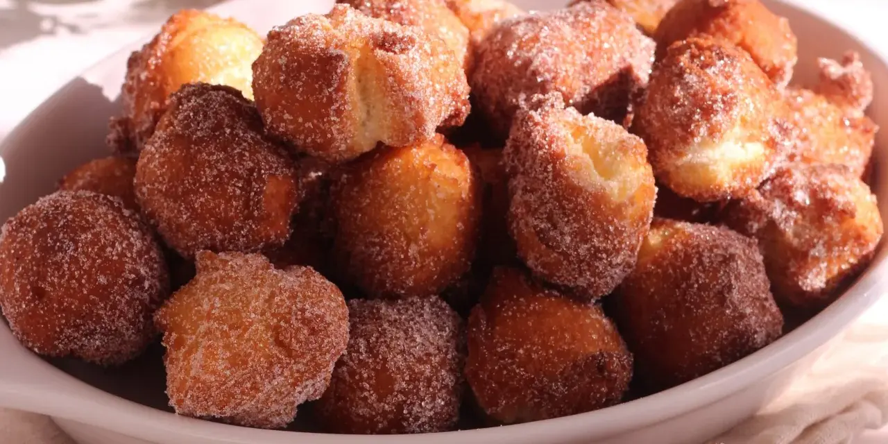 Un piatto colmo di castagnole ricetta della nonna, dorate e cosparse di zucchero. Un dolce che sa di casa e tradizione.