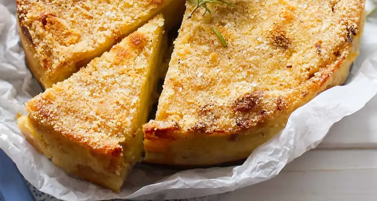 Gateau di patate alla siciliana dorato e croccante, guarnito con rosmarino fresco. Una fetta è già stata servita.