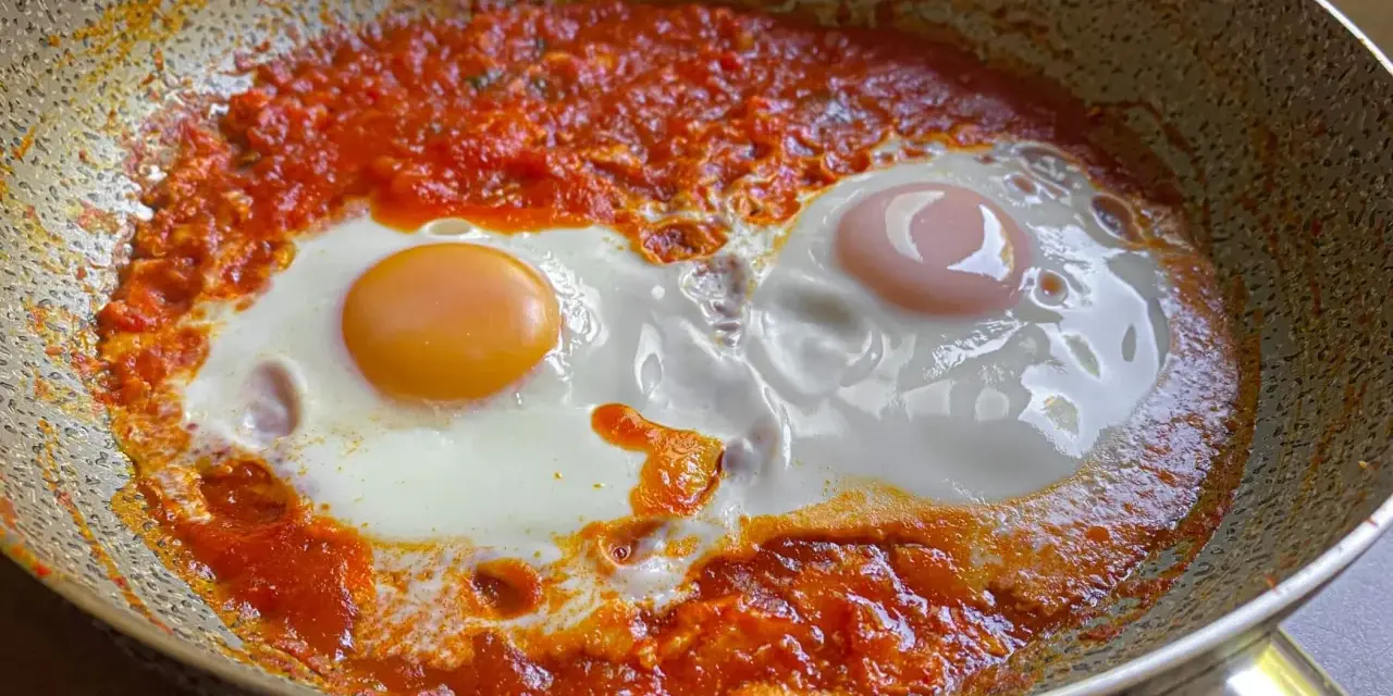 Uova in purgatorio, un piatto saporito con uova cotte in un sugo di pomodoro piccante, servite in padella.