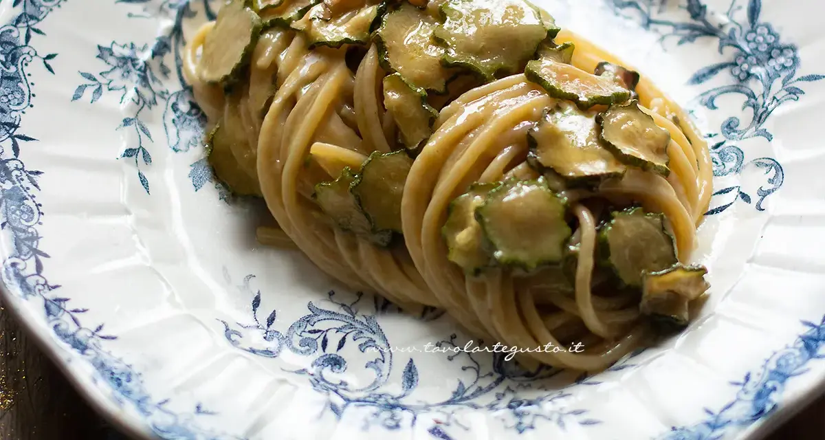 Spaghetti alla Nerano, un classico piatto campano con zucchine cremose e profumate, servito su un piatto decorato.